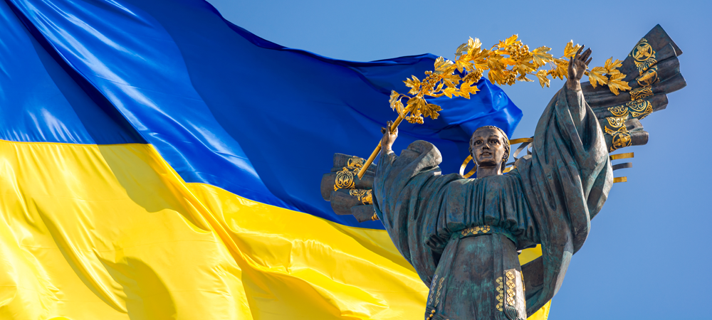 Monument of Independence of Ukraine in front of the Ukrainian flag. The monument is located in the center of Kiev on Independence Square.